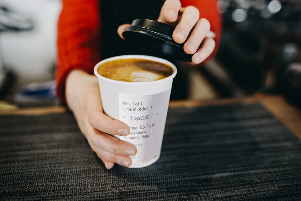 Close up of a direct thermal label on a hot cup of coffee being served.